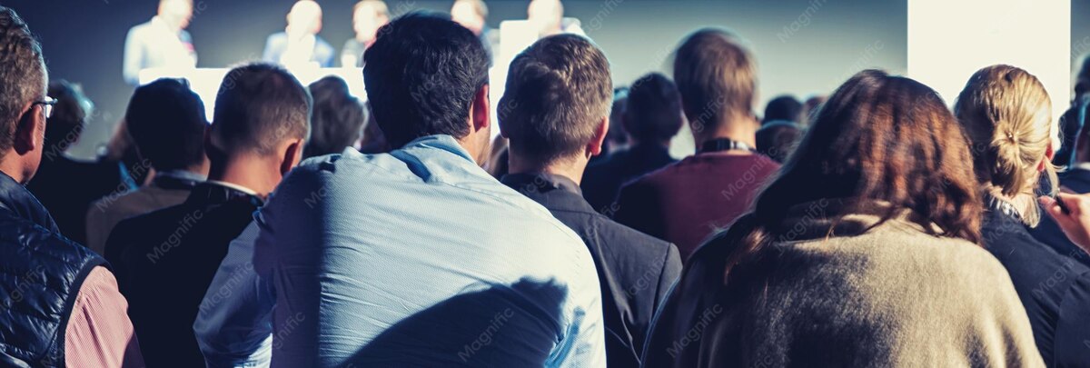 Audience in a conference hall listening to speakers on stage